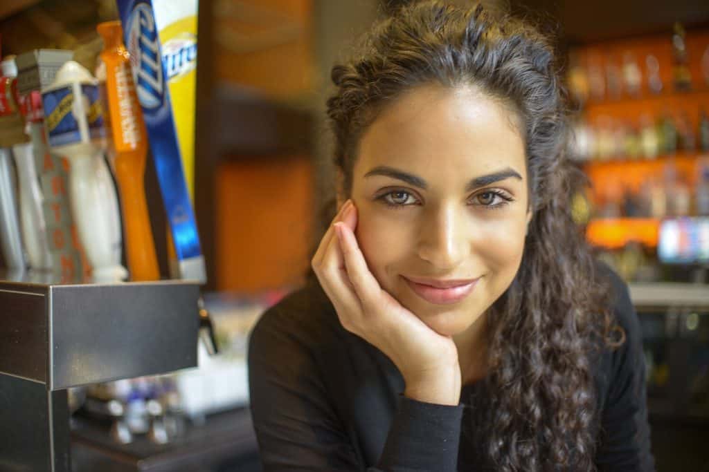 A young lady with beautiful hazel eyes looks and smiles at the camera