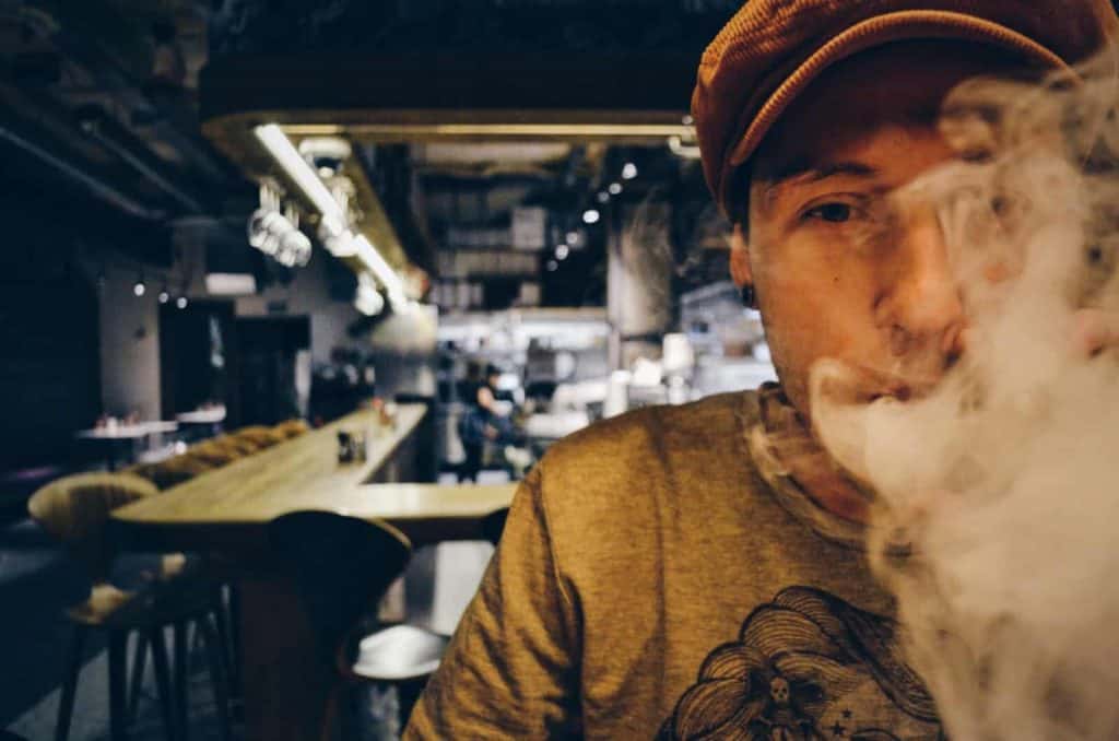 A smoker blowing a cloud of smoke at the camersa